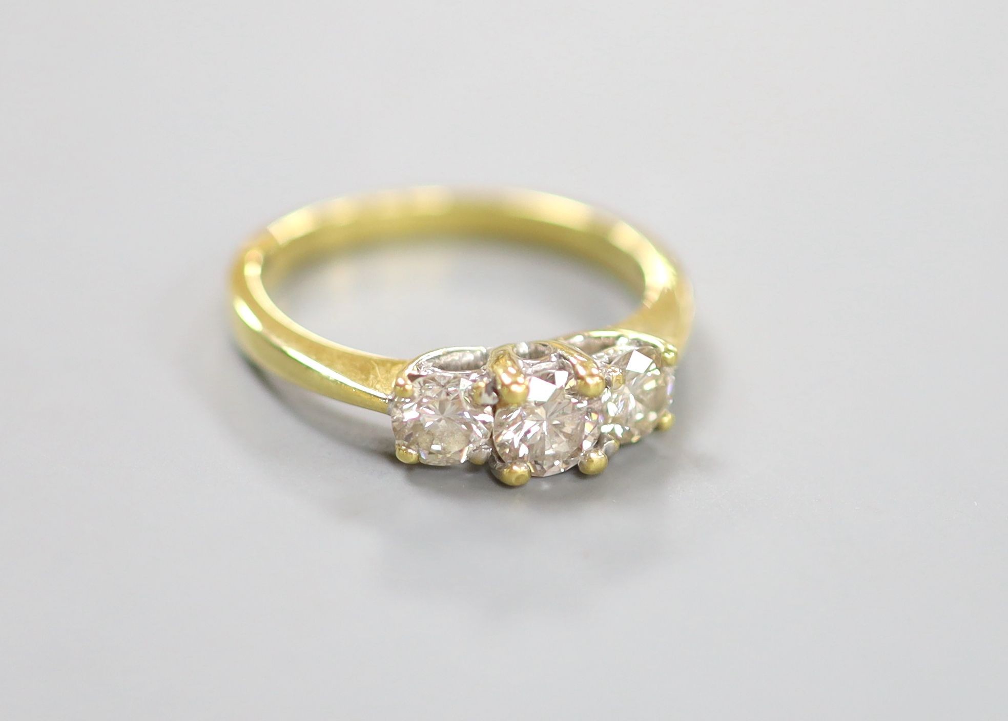 A modern 18ct gold and three stone diamond ring, size M, gross weight 3.4 grams.